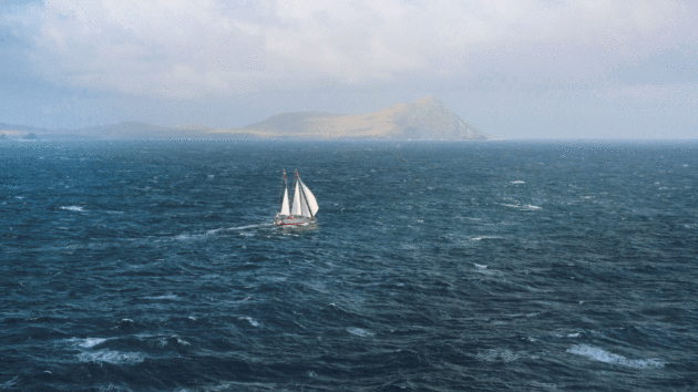 View of stormy seas with yacht in the distance