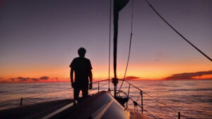 Elliot silhouetted on Fortaleza’s bow against a beautiful South Pacific sunset in the west