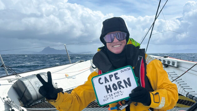 A crew member holding a whiteboard saying 'Cape Horn' on the yacht