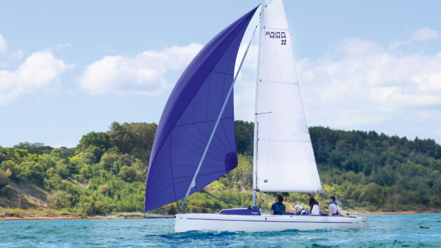 Yacht sailing in the water with a blue sail