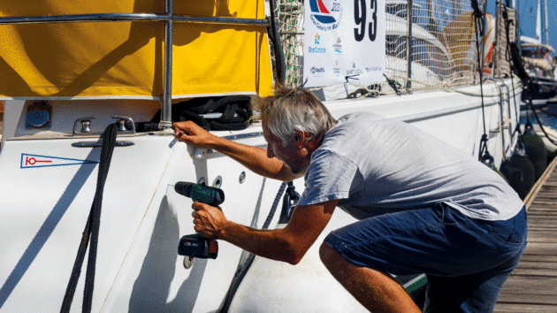 Someone holding a power drill next to a yacht