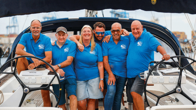 People smiling in blue polo shirts on a yacht