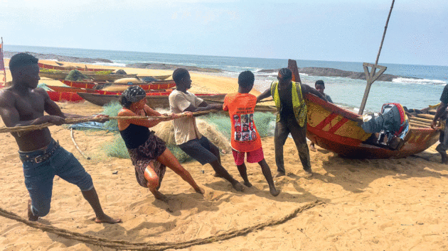 helping locals drag a fishing canoe up the beach