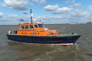 An orange and blue pilot boat in waters off Gravesend