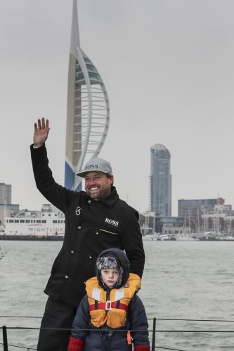 Alex Thomson waves with the Spinnaker Tower in Portsmouth in the background