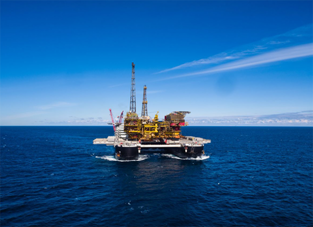 World's largest ship with an oil rig moving along a blue sea