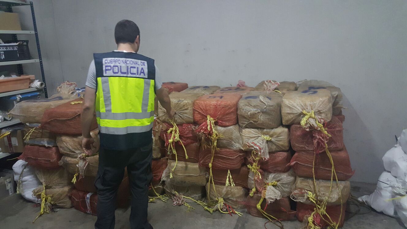 An officer in a yellow high viz jacket with bails of cocaine