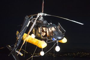 The remains of a wrecked helicopter being pulled out of a fjord