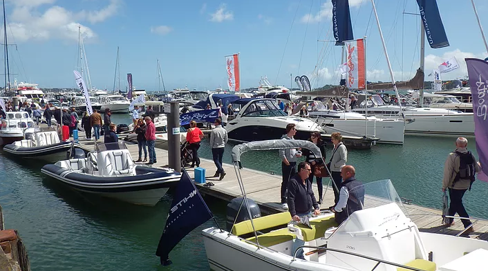 Visitors to the Poole Harbour Boat Show walk along a pontoon looking at motor boats