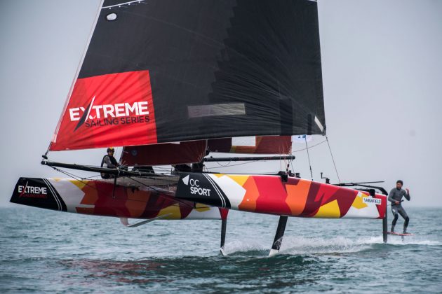 A sailor foils behind a foiling catamaran