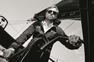 Alex Thomson wearing dark glasses helming