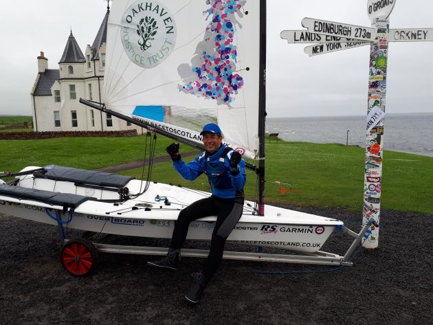 Dinghy sailor Ken Fowler with his white dinghy by the John o'Groats signpost