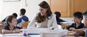 Dressed in a white jacket, Kate Middleton, Duchess of Cambridge talks to school children