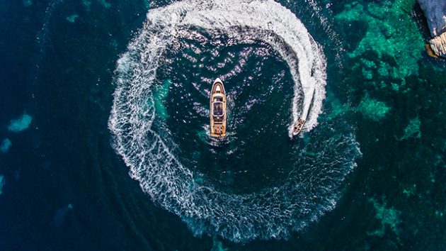 A tender/water scooter does circles around a bigger yacht