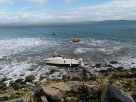 A white boat is stranded on rocks at Holyhead in Wales