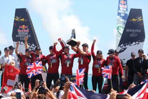 Sailors dressed in red tops hold a trophy high