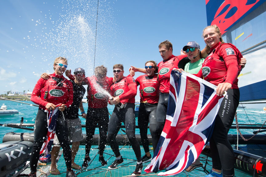 Dressed in red and holding a Union Jack flag, sailors from Land Rover BAR Academy celebrate winning the 2017 Red Bull youth America's Cup