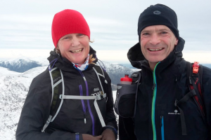 Sailing journalist Pip Hare in a red hat and Charles Hill in a black hat on top of a mountain training for the Three Peaks Yacht Race