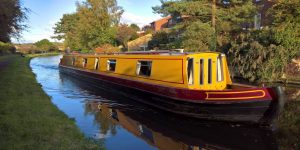 A yellow and red narrowboat on a stretch of a canal