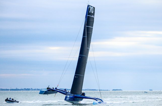 A maxi trimaran with a black sail taking part in a race on the Isle of Wight