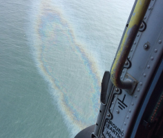 Helicopter flies over a sheen from a yacht which sank off the Washington Coast, USA