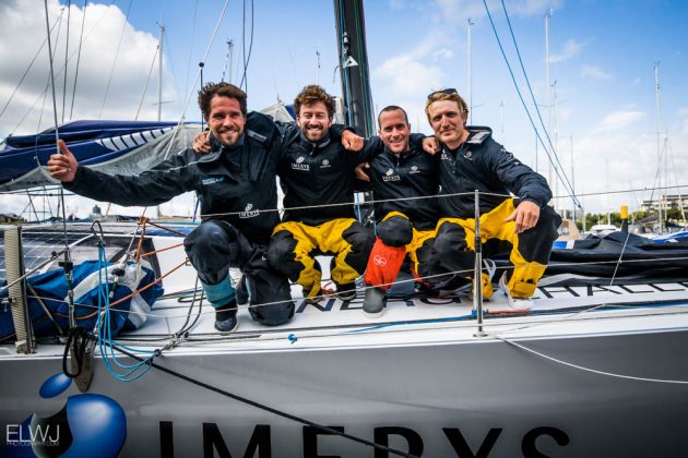 Immures crew dressed in wet weather gear on board their boat after finishing the Fastnet Race