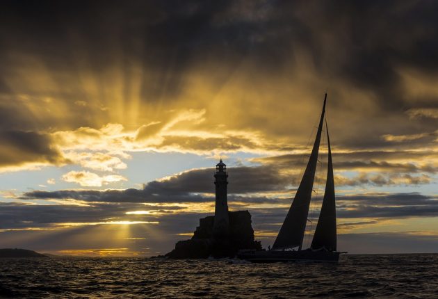 A yacht at day breaks with the Fastnet Rock in the background