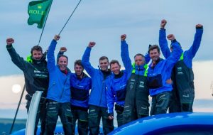 Dressed in blue, a trimaran crew celebrate after taking the line honours in the 2017 Fastnet Race