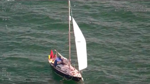 A yacht with white sails off the coast of Wales