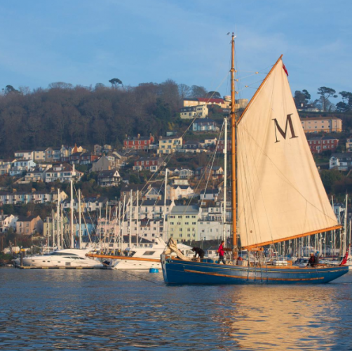 A wooden yacht with a white sail