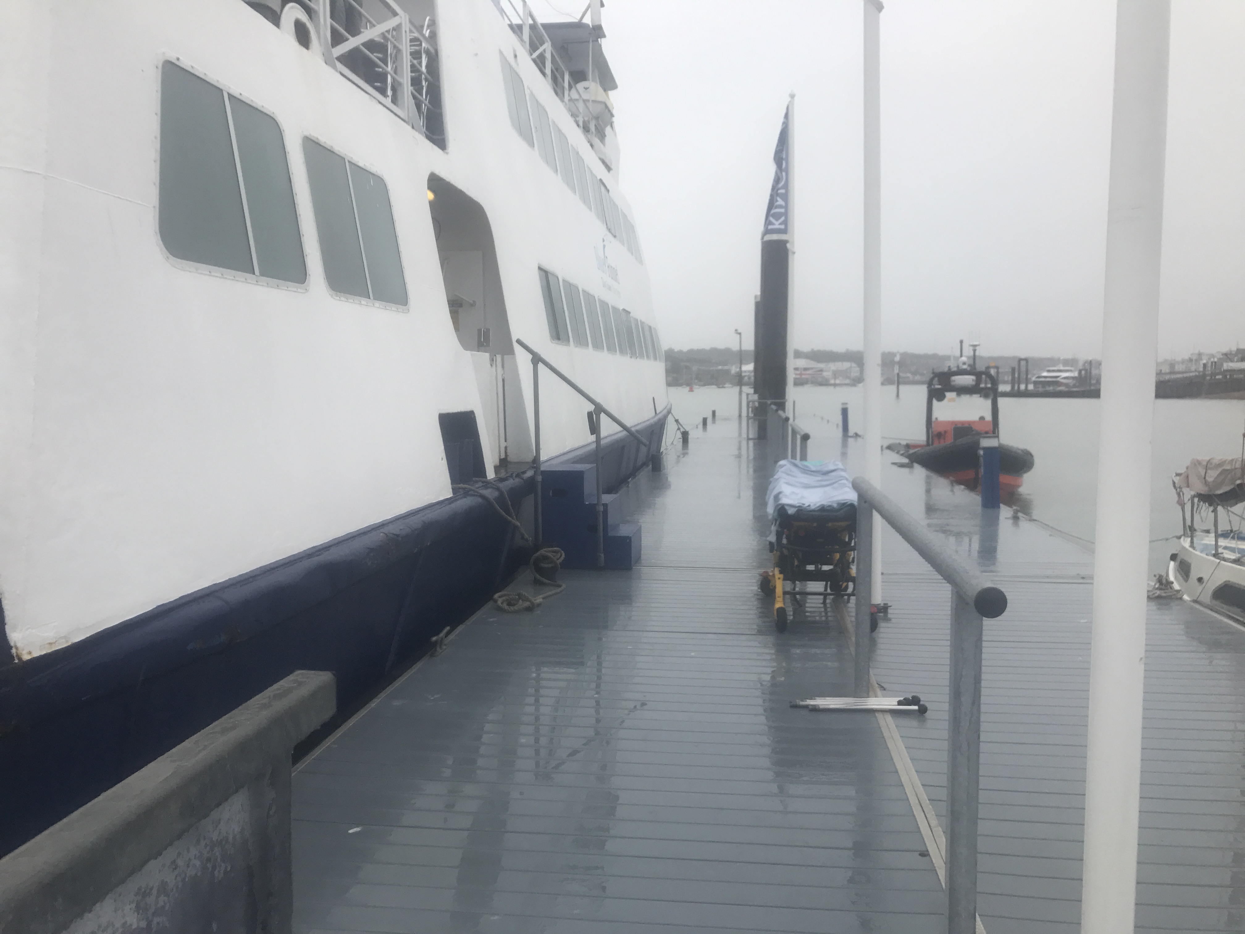 A ferry docked alongside a wet pier at Cowes with the GAFIRS lifeboat moored nearby