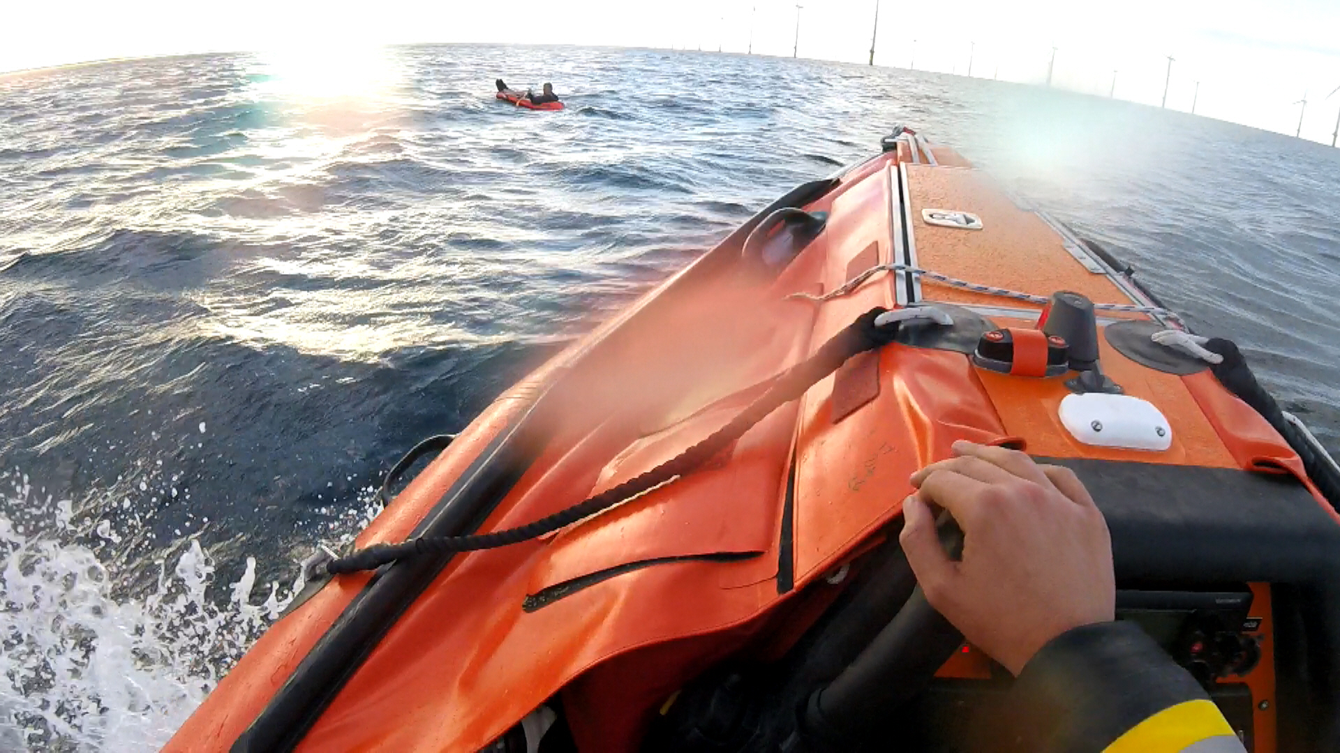 The crew of an orange lifeboat go to the aid of a man in a toy dinghy