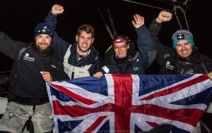 Four sailors wave a flag after beating the Length of Britain record