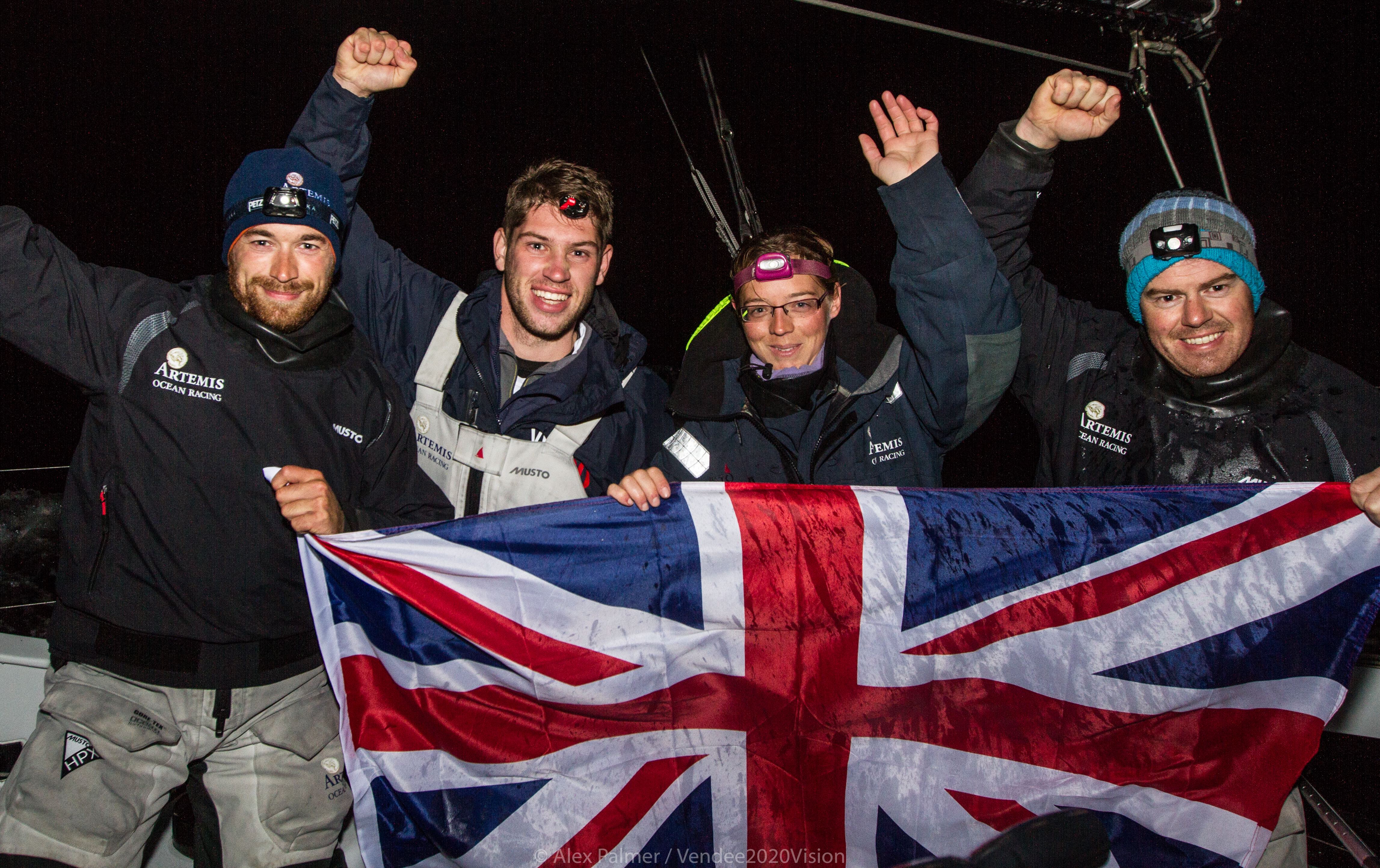 Four sailors wave a flag after beating the Length of Britain record