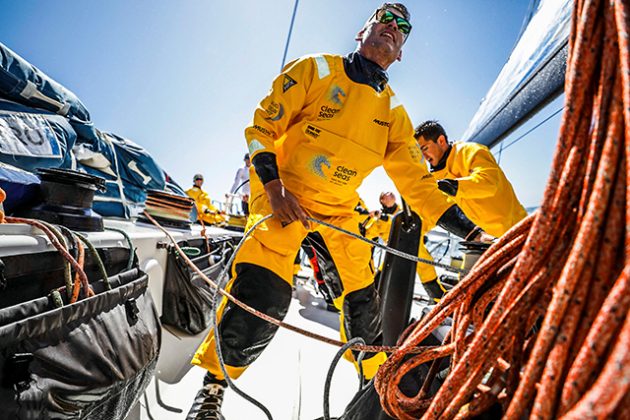 Sailors dressed in yellow sailing suits on board a yacht