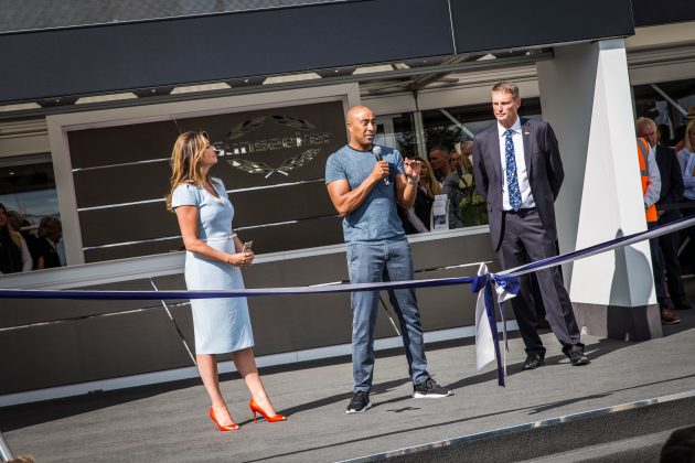 Three people prepare to cut the ribbon