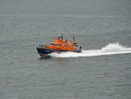 An orange all weather lifeboat speeding out of Plymouth