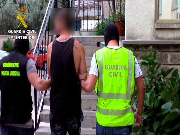 Police officers wearing jackets arrest a man in a black vest at Magaluf