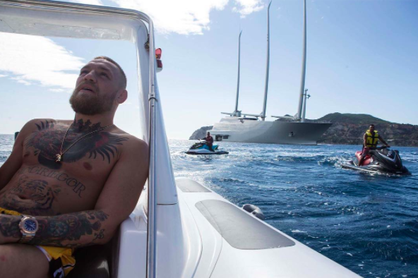 Conor McGregor on a yacht with sailing yacht a in the background