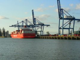 A red container ship at a port in London