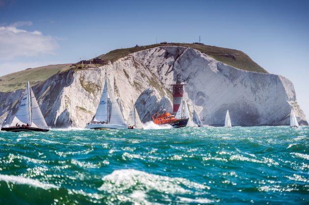 An orange lifeboat goes past the white cliff of the Isle of Wight