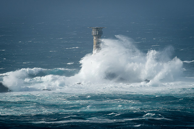 Waves break over a lighthouse as Storm Ophelia hits