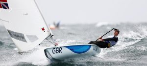 Dressed in black, Nick Thompson leans out in his laser, which has a white sail