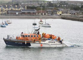 An orange all weather lifeboat assists a dismasted yacht at Wicklow