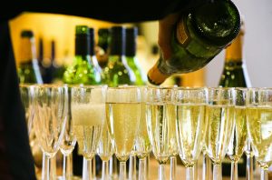 A person pouring from a bottle of sparkling wine into glasses on a bar top best cava under £25