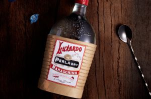 Bottle of Maraschino on a wooden bar with a barspoon