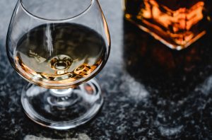 Close-up of a Cognac balloon glass and cognac in a decanter on a black marble table