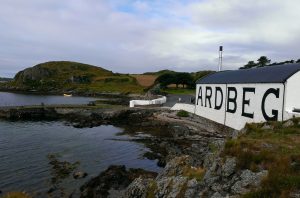 A whisky distillery building by the sea with hills and sky