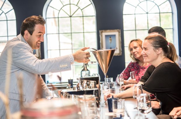 A row of people sitting at a bar tasting gin