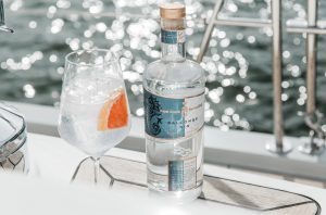 a glass and bottleof gin on the deck of a ship